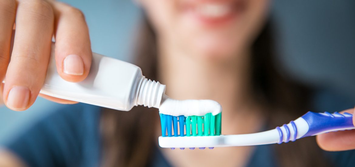 young girl putting toothpaste on her toothbrush